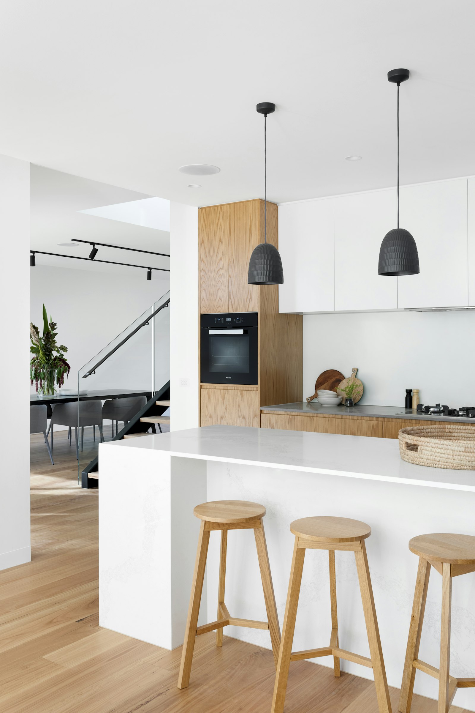 The working kitchen beyond, Miele ovens and steel, behind a door that closes