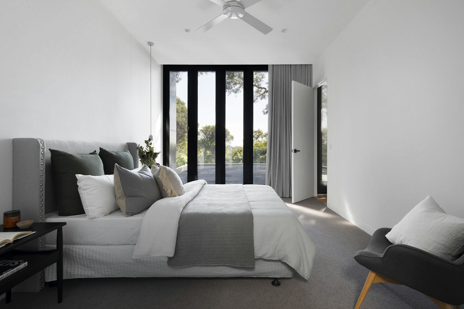 A suite in grey and cream, floor-to-ceiling glazing to the treetops