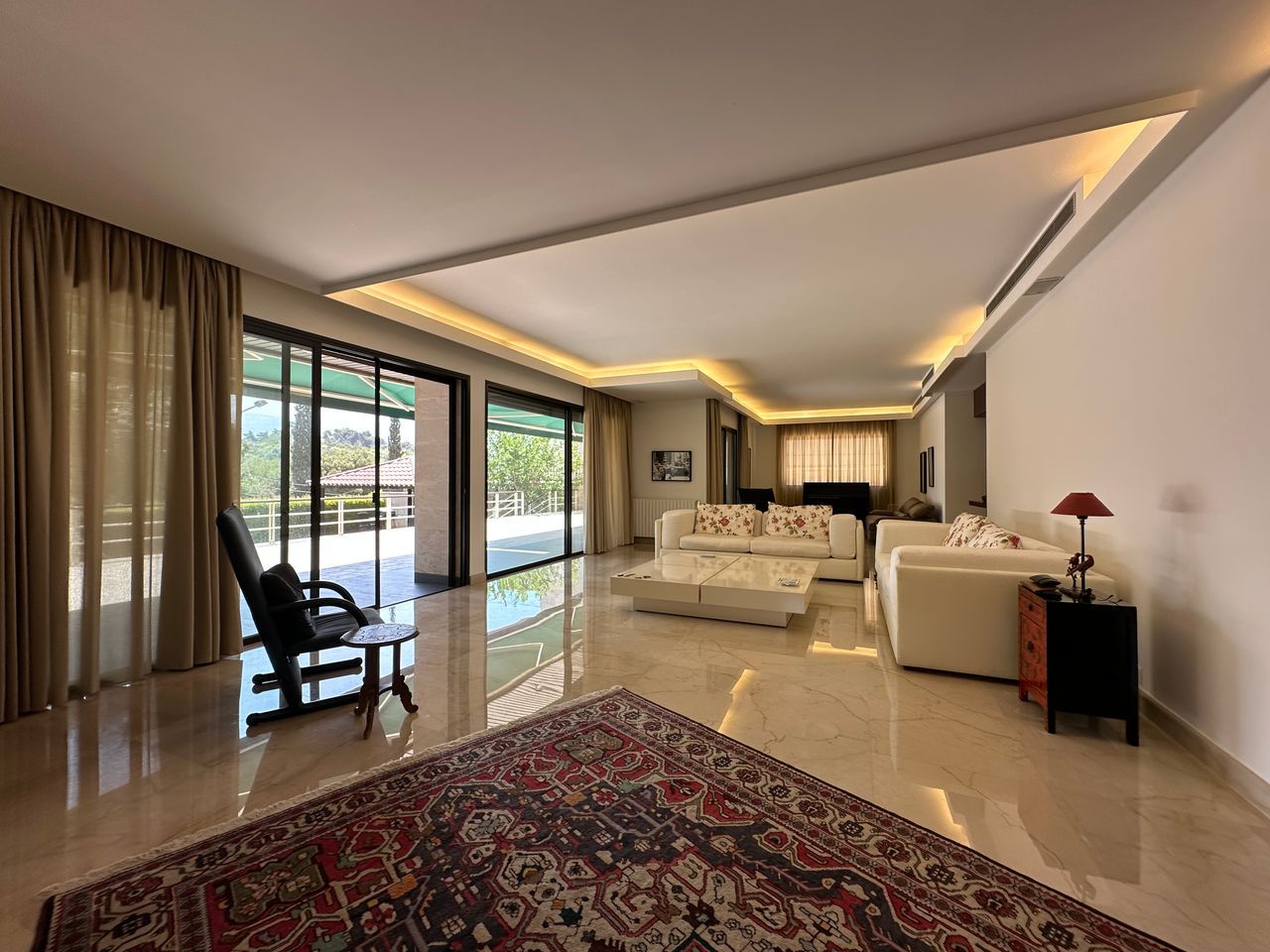 A glass-walled living room opening to a pool and garden